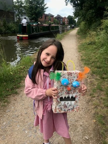 A shy girl holding up a box decorated to look like a monster